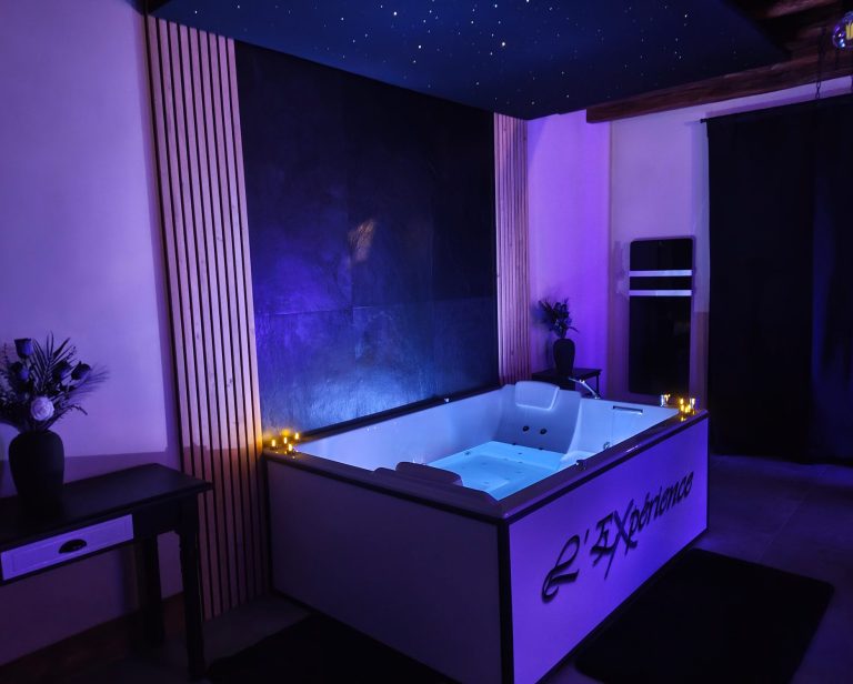 Balnéothérapie Bain balnéo éclairé de violet, décoré avec une cascade, dans une pièce moderne avec ciel étoilé